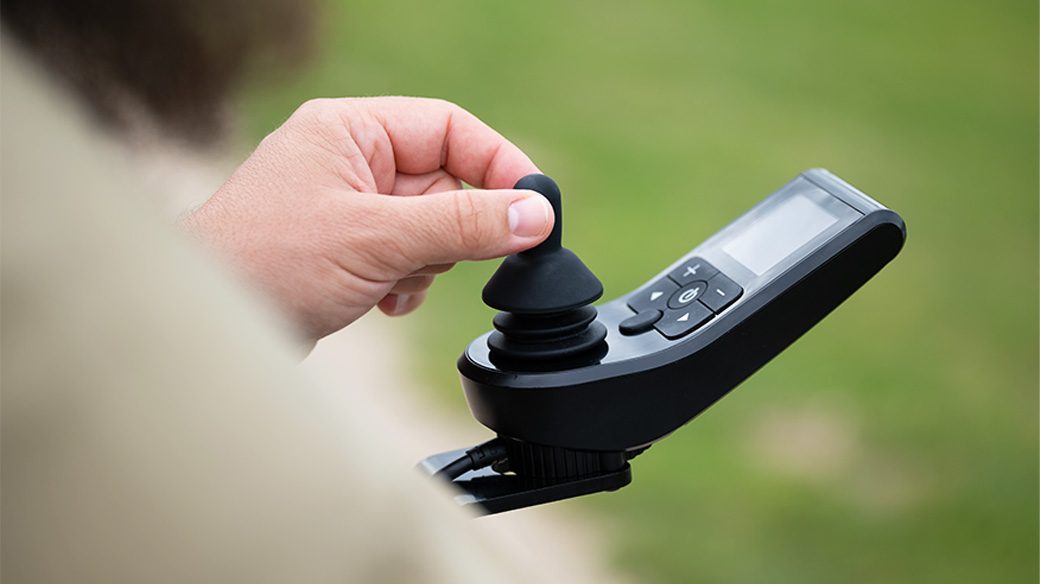 Hand am Joystick des Bedienmoduls eines ergoflix Elektrorollstuhls